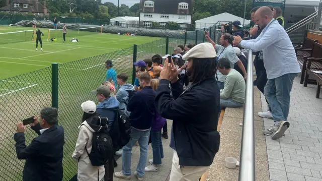 lots of fans behind a net taking a picture