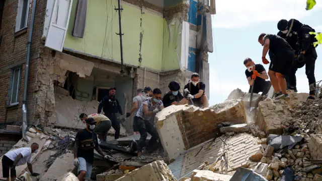 Residents help rescuers remove debris at a site of a building damaged during Russian missile strikes.