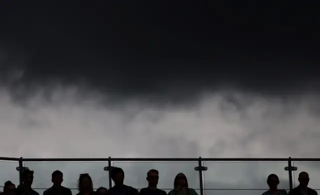 Dark grey clouds overhead at Wimbledon as fans sit in the stands