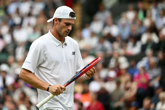 Tommy Paul looks down at his racquet