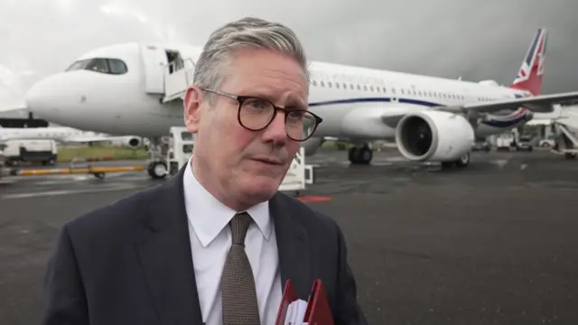 Keir Starmer speaks with media outside of a plane parked on the tarmac