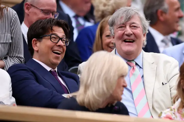 Michael McIntyre and Stephen Fry laugh with each other in the Royal Box