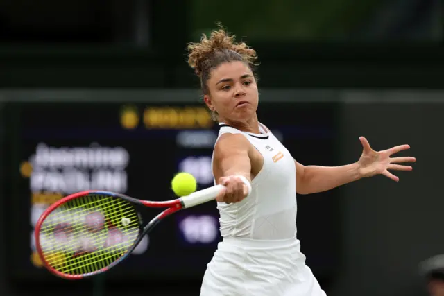 Jasmine Paolini hits a forehand shot wearing an all-white outfit