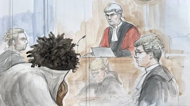 Rudakubana covers his face in a jumper while a judge looks on