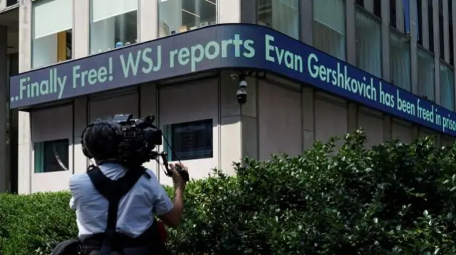 Outside shot of WSJ headquarters with a news ticker saying "Finally Free! WSJ reports Evan Gershkovich has been freed..."