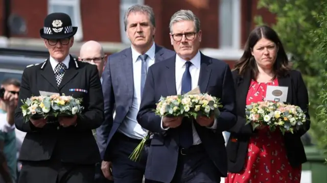 British Prime Minister Keir Starmer (C-R) arrives to lay flowers at the scene of a stabbing attack on Hart Street in Southport, Britain, 30 July 2024.