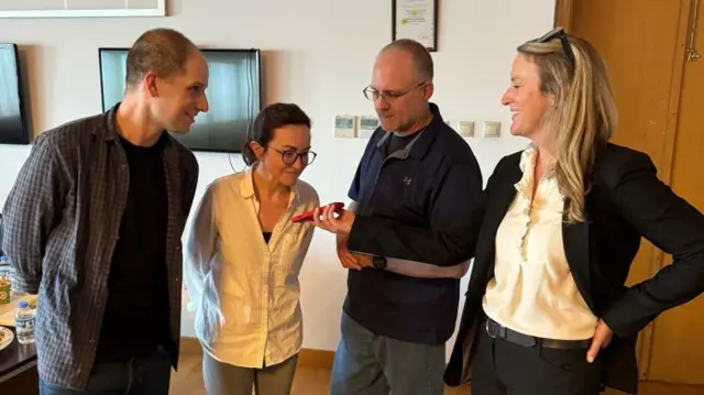 Evan Gershkovich, Alsu Kurmasheva and Paul Whelan on the phone with President Joe Biden (phone held by U.S. Government Employee).