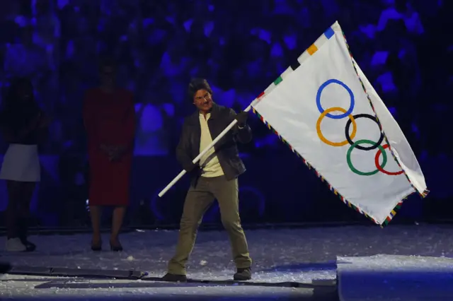 Actor Tom Cruise holds the Olympics flag during the closing ceremony