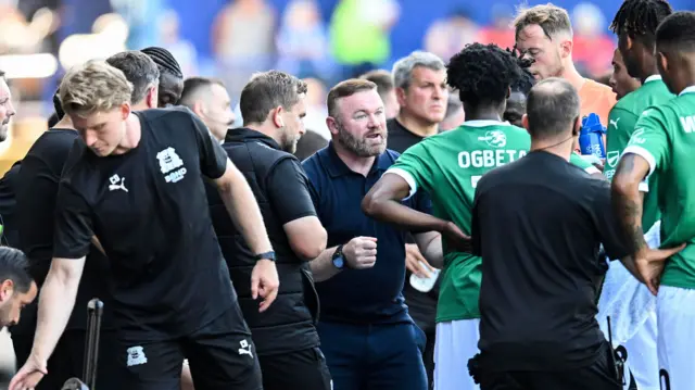 Wayne Rooney talks to his players during a break in play