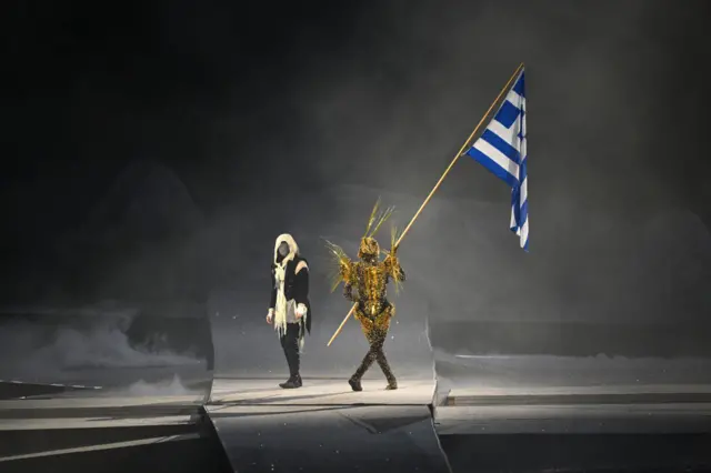 A performer holds Greece's flag during the closing ceremony of the Paris 2024 Olympic Games at the Stade de France