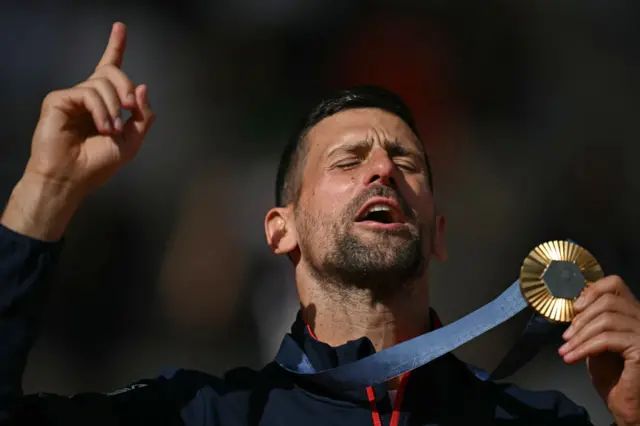 old medallist, Serbia's Novak Djokovic poses with his medal on the podium at the presentation ceremony for the men's singles tennis event on Court Philippe-Chatrier at the Roland-Garros Stadium