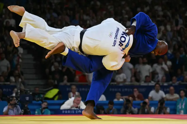 South Korea's Kim Min-jong and France's Teddy Riner (Blue) compete in the judo men's +100kg gold bout of the Paris 2024 Olympic Games at the Champ-de-Mars Arena