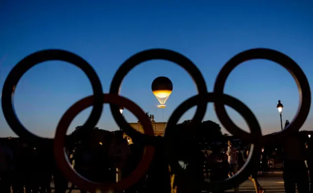 Olympic Games cauldron floats above Paris behind the Olympic rings