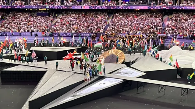 Athletes parade with flags into the Stade de France