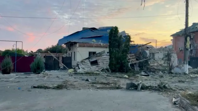 Landscape shot of a house and surrounding buildings that have been hit