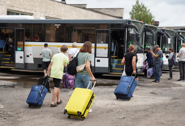 People carry suitcases onto coaches in the Kursk region