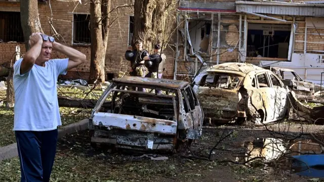 A man reacts while standing next to burnt-out remains of cars in the courtyard of a multi-storey residential building, which according to local authorities was hit by debris from a destroyed Ukrainian missile, in the course of Russia-Ukraine conflict in Kursk, Russia August 11, 2024.