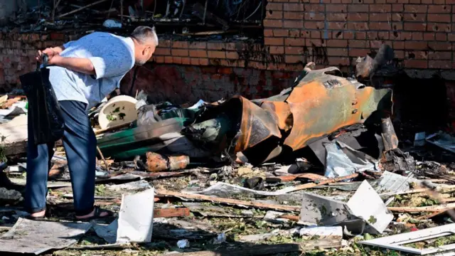 A man looks at debris near a multi-storey residential building in Kursk