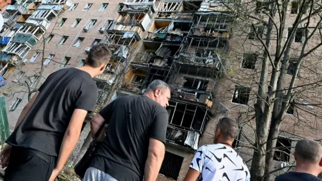 People gather in the courtyard of a multi-storey residential building,