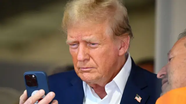 Donald Trump talks on the phone in the McLaren garage prior to the F1 Grand Prix of Miami at Miami International Autodrome on May 05, 2024 in Miami, Florida.