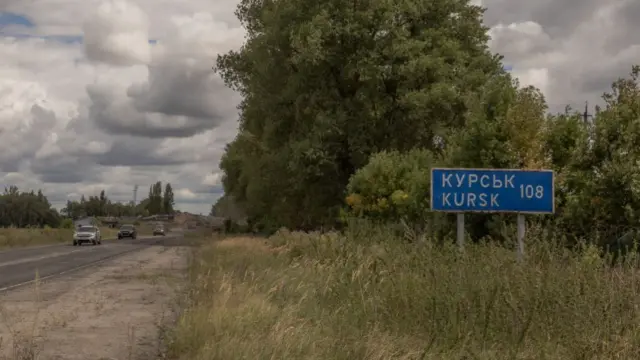 This photograph shows Ukrainian military vehicles driving past the border crossing point with Russia, in the Sumy region