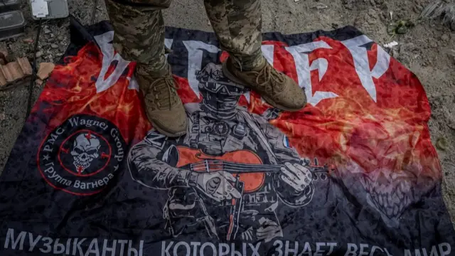 A Ukrainian serviceman stands on a flag of Russia's mercenary group Wagner, amid Russia's attack on Ukraine, near the Russian border in Sumy region, Ukraine August 13, 2024.