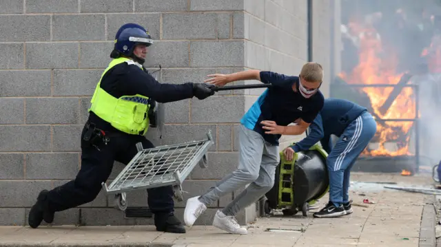 A demonstrator runs away from a police officer during an anti-immigration protest in Rotherham