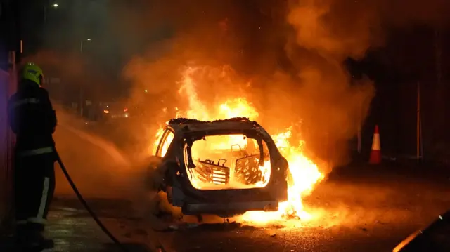 A firefighter tries to put out a car set alight in Hartlepool