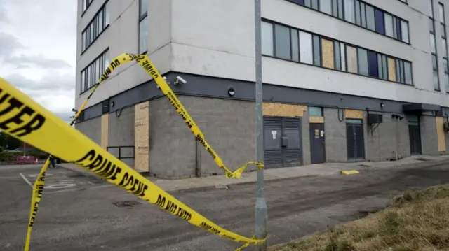 Hotel behind a police cordon, with boarded up doors and windows