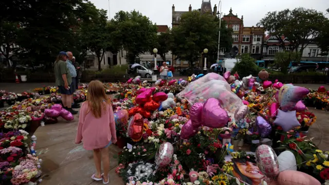 Members of the public lay flowers in memory of the three children who died