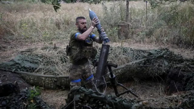 A serviceman prepares a a 120-mm mortar