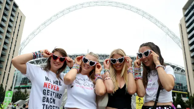 Fans wear Taylor Swift glasses outside Wembley Stadium arch