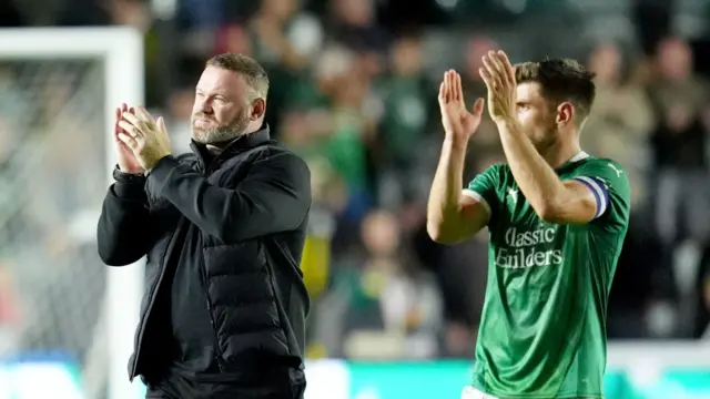 Wayne Rooney and a Plymouth player applaud the team's fans after their win over Cheltenham