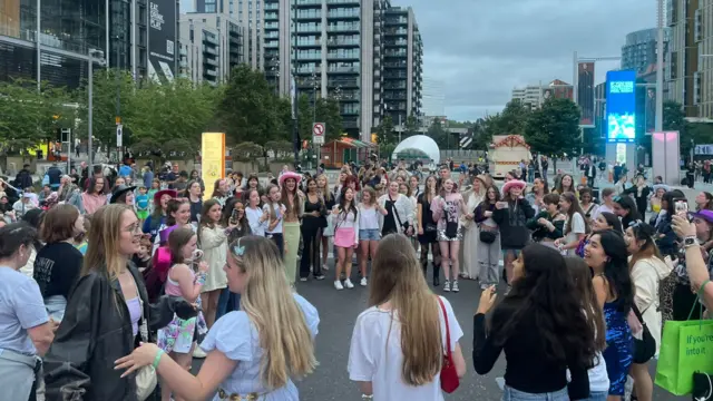 Swifties dance and sing outside the stadium perimeter