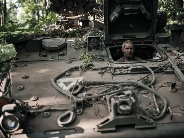 A Ukrainian mechanic rests in an American Stryker armoured vehicle after returning from a combat mission in the Kursk region