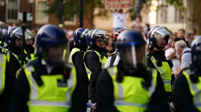 Police wearing helmets try to keep a protest on Whitehall under control last month