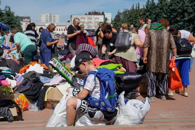 Group of people in downtown Kursk collecting clothes with a child holding a toy in the foreground