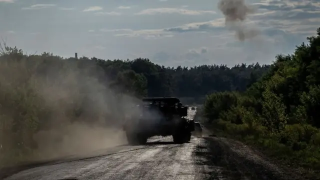 Ukrainian armoured vehicles drive down a road near the Russian border in the Sumy region