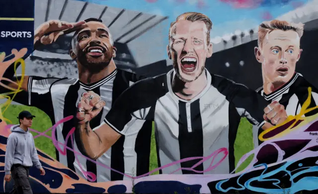 Fan walks past huge Newcastle mural of  Wilson, Burn and Longstaff