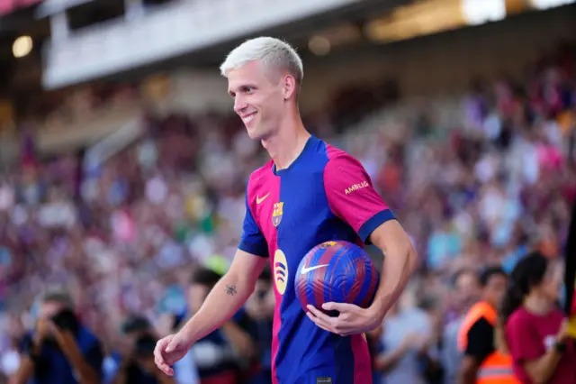 Dani Olmo smiling with a ball under his arm