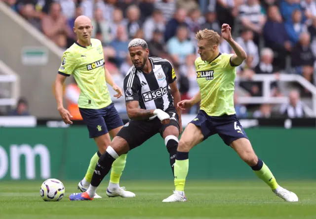 Joelinton shoots under pressure from two defenders