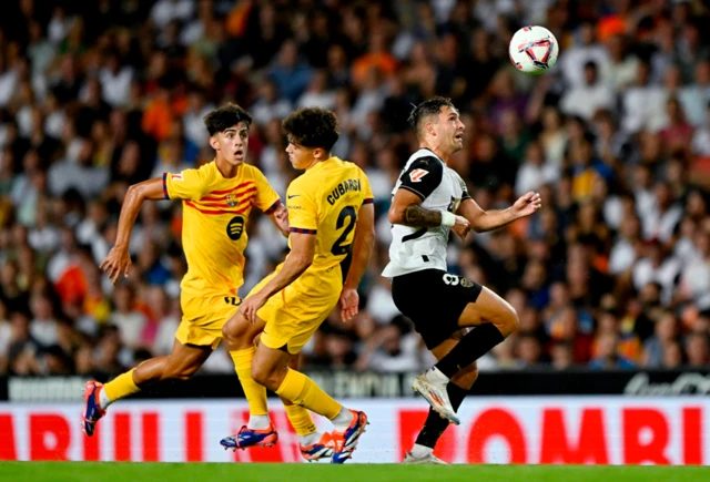 Valencia's Hugo Duro in action with Barcelona's Pau Cubarsi and FC Barcelona's Marc Bernal