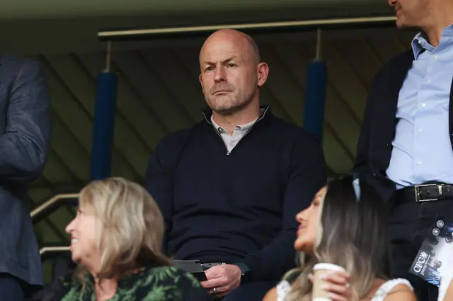 England interim boss Lee Carsley sits in the stands holding a programme