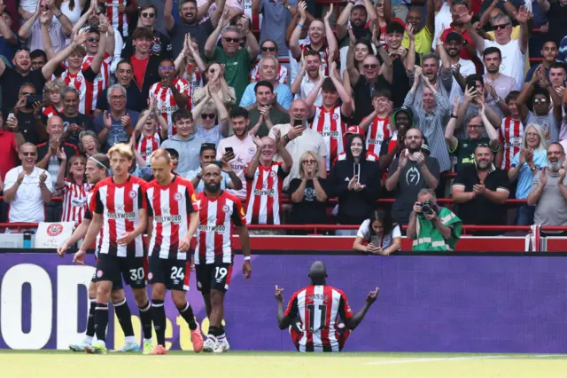 Yoane Wissa celebrating by sitting on the ground in front of the Brentford fans