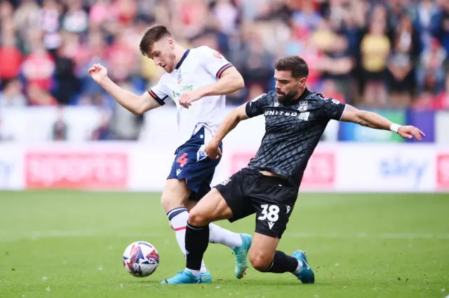 George Thomason of Bolton Wanderers is challenged by Elliot Lee of Wrexham