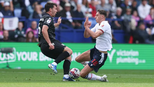 Eoin Toal of Bolton Wanderers and Thomas O'Connor of Wrexham collide going for the ball