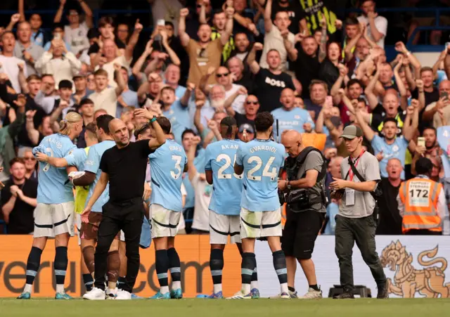 Guardiola waves the City players over to celebrate with the away fans