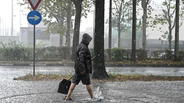 A person walks in a waterlogged street following a heavy storm in Turin, northern Italy, 14 August 2024.