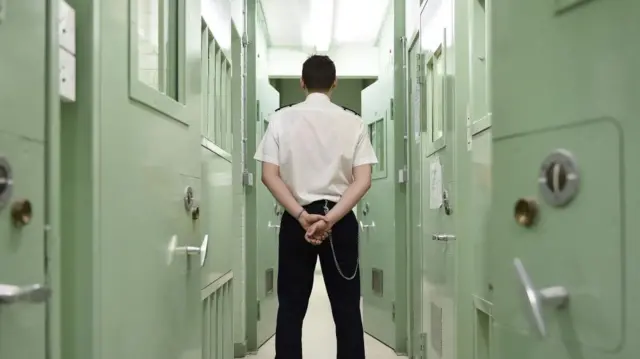 A prison officer surrounded by cell doors