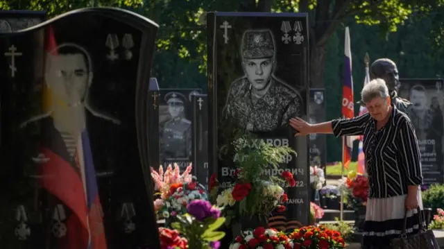 A woman grieves standing near the grave of a Russian serviceman on the central cemetery in Kursk, Russia, 18 August 2024.